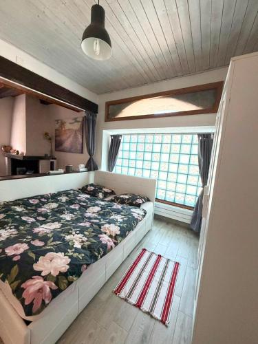 a bedroom with a bed with a floral comforter and a window at Il Nido Viola in Arbedo-Castione