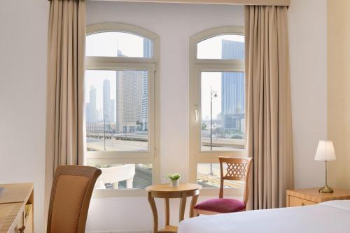 a hotel room with a bed and two windows at Roda Al Murooj Residences in Dubai