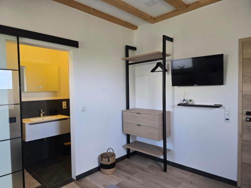 a bathroom with a sink and a tv on a wall at Scheuneria, Gästehaus in Dockweiler