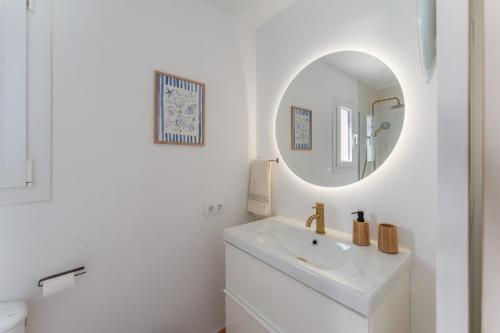a white bathroom with a sink and a mirror at Villas 19 Estrellas in Cala en Bosc