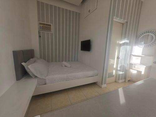 a small bed in a white room with a window at Casa Bahia Dive Resort in Mabini