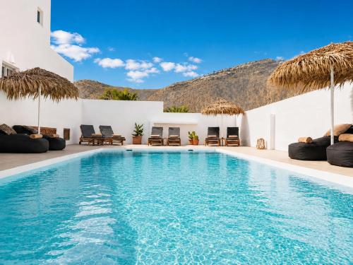 a pool with chairs and umbrellas in a resort at Aegeeis in Perissa