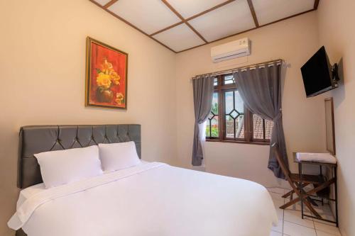 a bedroom with a white bed and a window at Agni Homestay in Yogyakarta
