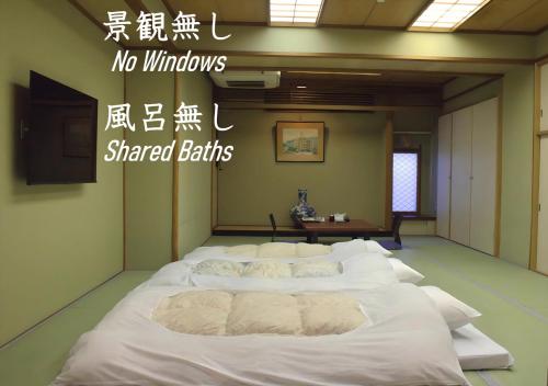 a large white bed in a room with writing on the wall at Hotel Kan-ichi in Atami