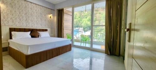 a bedroom with a bed and a large window at Yogvan Luxury 1BHK Apartments Tapovan Rishikesh in Rishīkesh