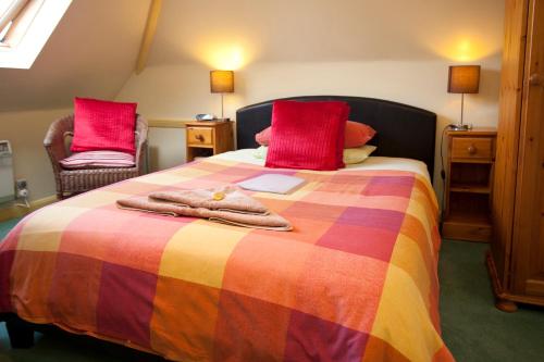 a bedroom with a bed with a colorful blanket and two chairs at Cranston House in East Grinstead