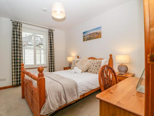 a bedroom with a bed and a desk and a window at Capella Cottage in Keswick