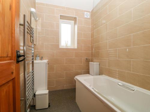 a bathroom with a tub and a toilet and a sink at Capella Cottage in Keswick