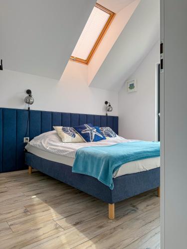 a bedroom with a bed with blue sheets and a window at Domki Nord Star in Władysławowo