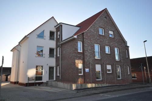 a brick and white building next to a street at Nr 57 - Ferienwohnung Mühlenstraße in Carolinensiel