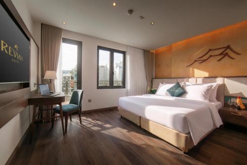 a bedroom with a bed and a desk and a television at Reviah Hotel in Hanoi
