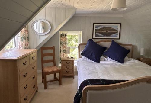 a bedroom with a bed with blue pillows and a staircase at Rubybank Bothy, overlooking Loch Fyne in Strachur