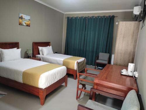 a hotel room with two beds and a desk at GreenLand Hotel in Kasane