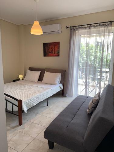 a bedroom with a bed and a couch and a window at Alasrooms Γ1 in Missolonghi