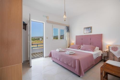 a bedroom with a pink bed and a large window at Dorothy's Seaview Apartment in Haraki