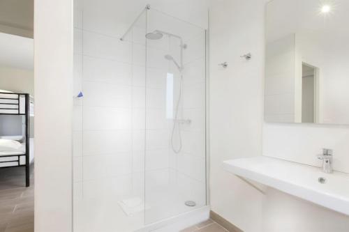 a white bathroom with a shower and a sink at Enjoy Hostel in Paris