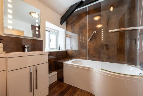 a bathroom with a tub and a glass shower at Duchy - Treworgie Barton Cottages in Bude