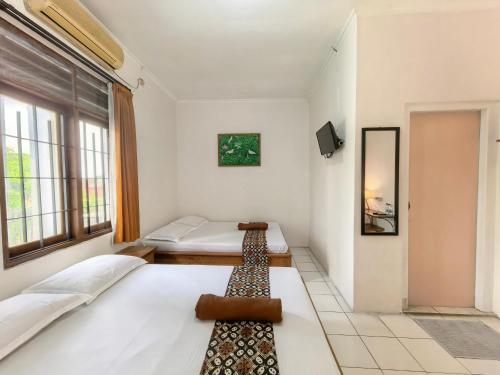 a bedroom with two beds and a window at Santalum Hotel Yogyakarta in Yogyakarta