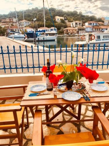 a table with plates and flowers on top of a harbor at Joanna Seaside House in Meganisi