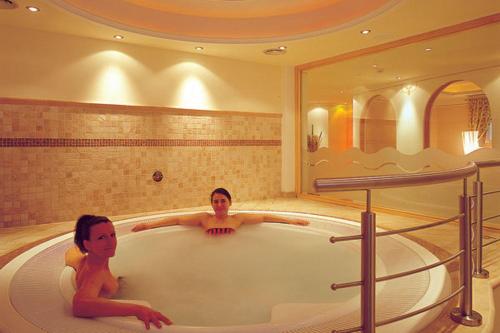Hotel San Leonardo في باديا: رجل وامرأة يجلسان في حوض الاستحمام