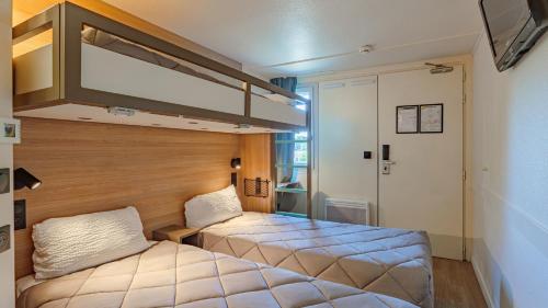 a bedroom with two beds in a room with a large bed at Premiere Classe Biarritz in Biarritz