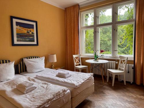 a bedroom with two beds and a table and windows at Villa am Peetzsee Unterkunft am See in Grünheide mit Parkplatz, Self Check-in, Küche, WLAN, Nähe Tesla Berlin in Schlangenluch