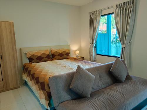 a bedroom with a bed and a couch and a window at Na Na Twinhouse in Bang Tao Beach