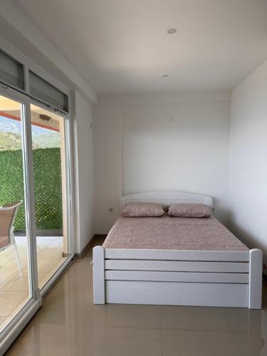 a white bedroom with a bed and a sliding glass door at SunsetEscape Apartments Utjeha in Utjeha