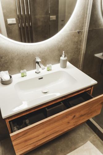a bathroom with a white sink and a mirror at Pioneer house - app with free parking place, terrace and private garden in Koliba
