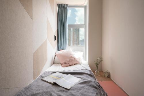 a small bedroom with a bed with a window at Weave Studios - Olympic in Hong Kong