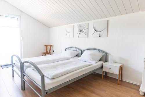 a bed in a white room with two pictures on the wall at Ferienhaus Steinhoff in Marsberg