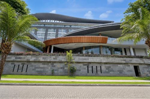 a building with palm trees in front of it at Sunday Hotel Antero Jababeka in Cikarang