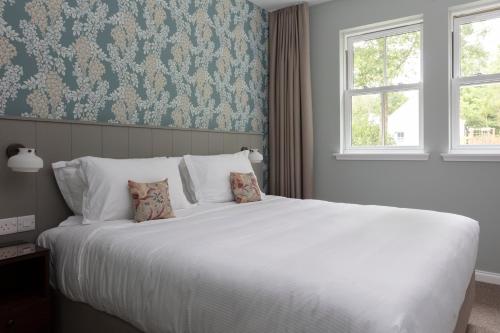 a bedroom with a large white bed and a window at Roxburghe Cottages, part of Destination by Hyatt in Kelso