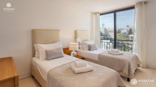 two beds in a room with a window at Emily in Vale do Lobo
