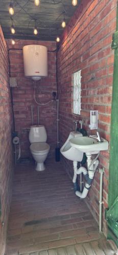 a brick bathroom with a sink and a toilet at Folwark Pod Bukowcem in Podzamcze