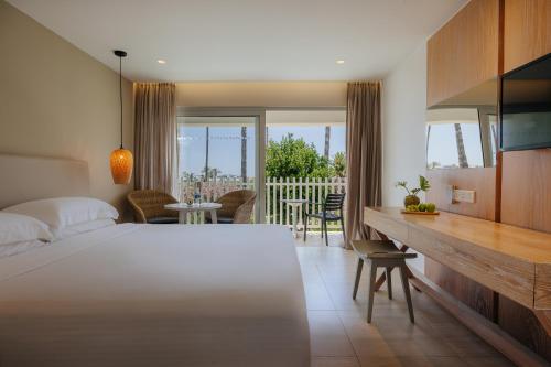 a bedroom with a bed and a dining room with a balcony at Nissi Beach Resort in Ayia Napa