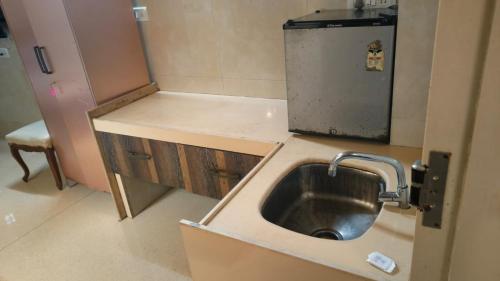 a small kitchen with a sink and a refrigerator at Hotel Oliver in Mumbai