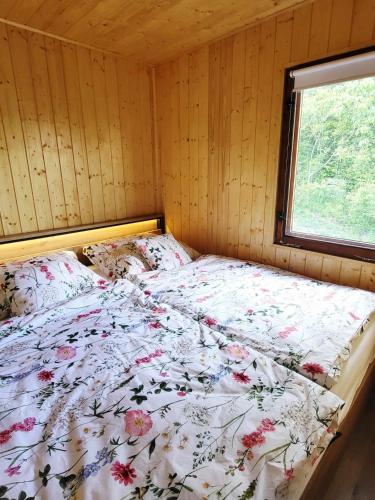a bed with a floral comforter in a room with a window at Broumík - chata s výhledy in Opočno