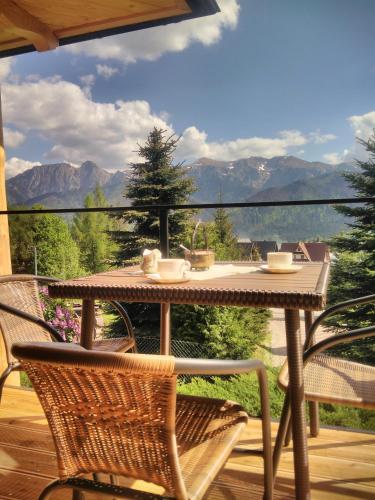 a table and chairs on a deck with a view of mountains at Domek Pod Wierchami z Jacuzzi in Kościelisko