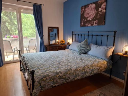 a bedroom with a bed with blue walls and a balcony at Baker's Pond Apartment Two in Velden am Wörthersee