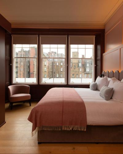 a bedroom with a large bed and windows at The Address Wren in Glasgow