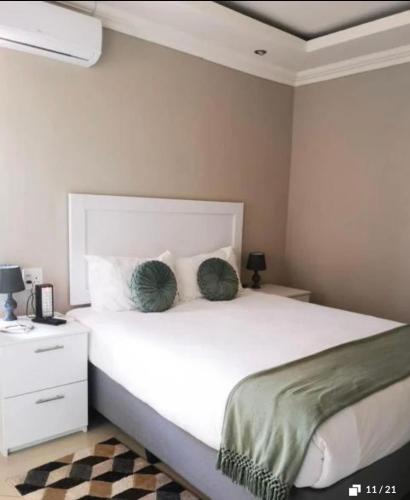 a bedroom with a white bed with two green pillows at Bosago lodge and Spa in Burgersfort