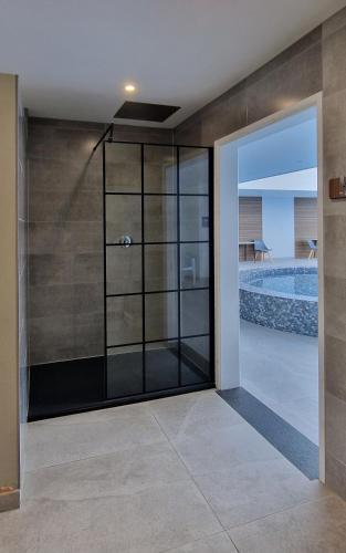 a glass shower door with a view of a swimming pool at Widdy Bay View in Widemouth Bay