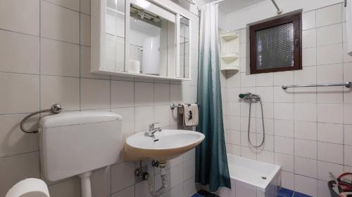 a bathroom with a sink and a toilet and a mirror at Villa Rossy by Villas Guide in Pavicini