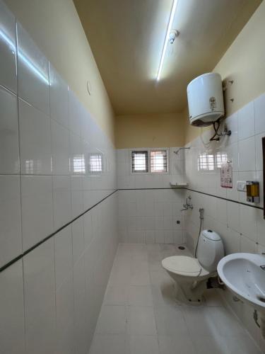 a white bathroom with a toilet and a sink at Pravaha Hostel in Bangalore