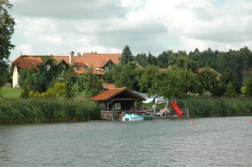 a house with a dock and a boat on the water at Majątek Giże Marczak in Olecko