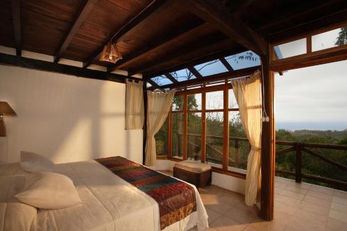 a bedroom with a bed and a large window at Samai Lodge Holistic Living in Olón