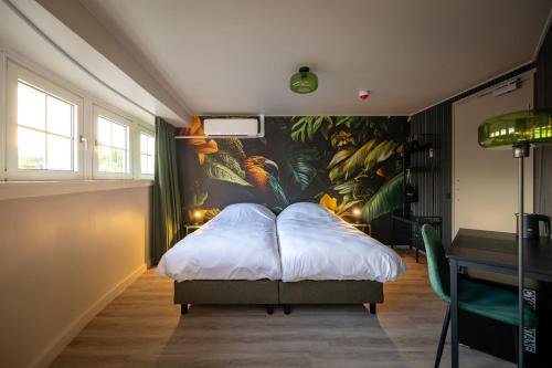 a bedroom with a bed with a painting on the wall at Stadshotel Tante Annie's in Oldenzaal