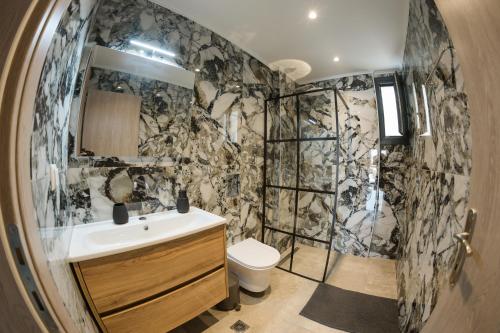 a bathroom with a shower and a sink and a toilet at Sweet Suites in Nea Peramos