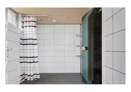 a bathroom with white tiled walls and a shower at Central City nest in Haparanda